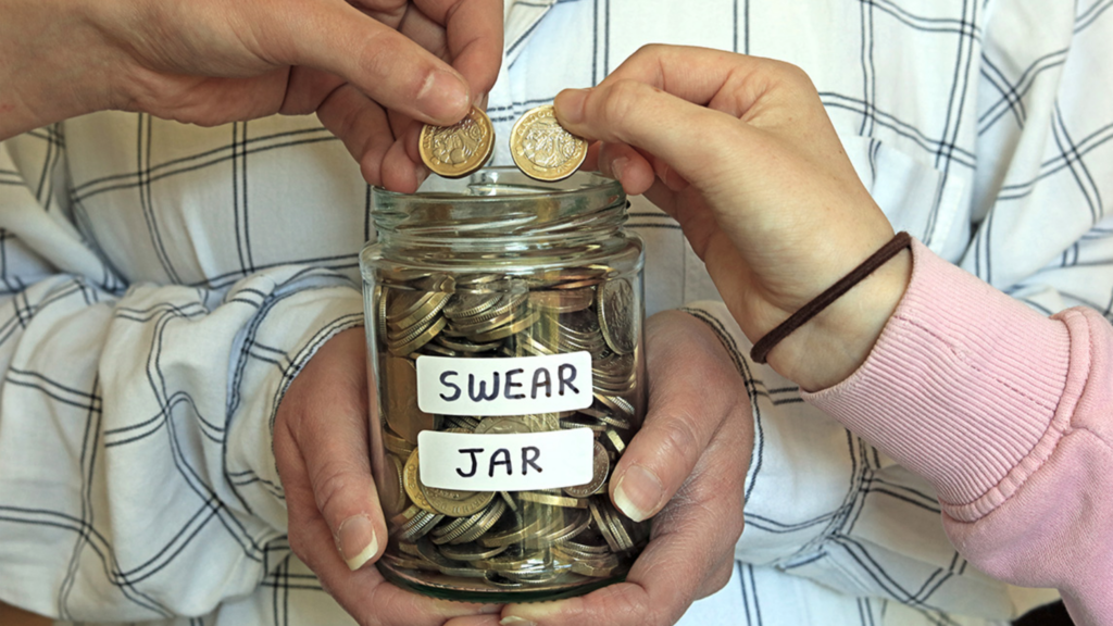 Person with checkered shirt holding swear jar while two people put money in it